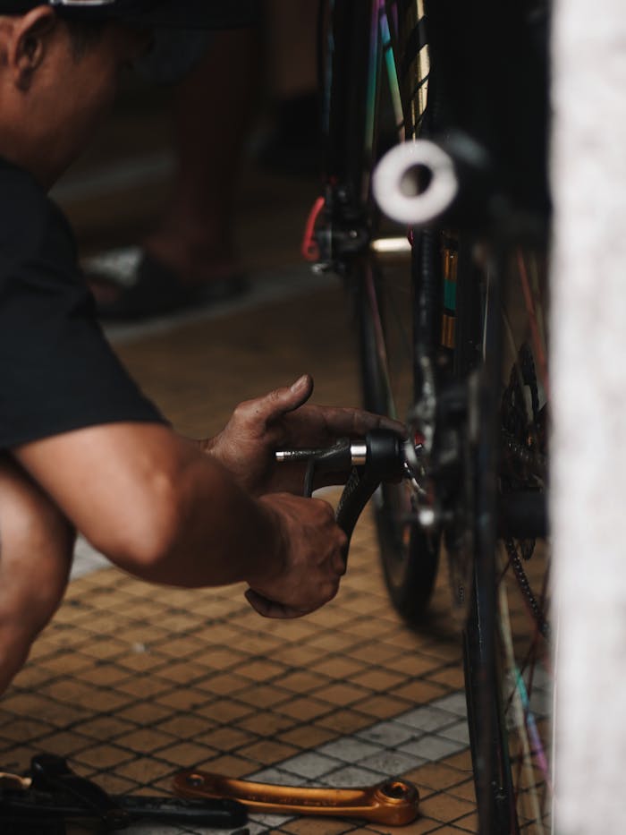 A person fixes a bicycle wheel indoors, focusing on maintenance tasks.